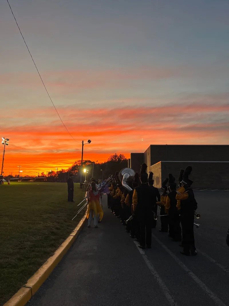 Band members lined up under a bright orange sunset